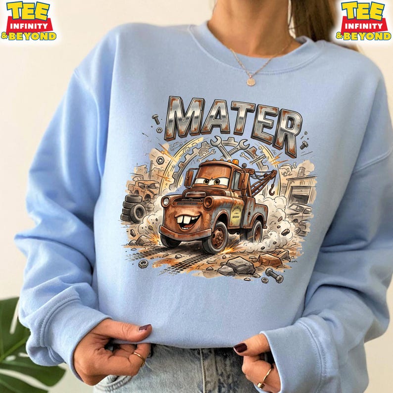 May include: Light blue sweatshirt featuring a cartoon illustration of Mater from the movie Cars. The design includes the name "MATER" in a metallic font, a rusty tow truck, and a background of tools and gears.