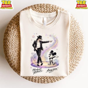 Può includere: T-shirt color crema con grafica di Michael Jackson e Topolino. Jackson è raffigurato in nero, che indica, con Topolino accanto. La maglietta include il testo "Michael Jackson" e "Mickey Mouse".