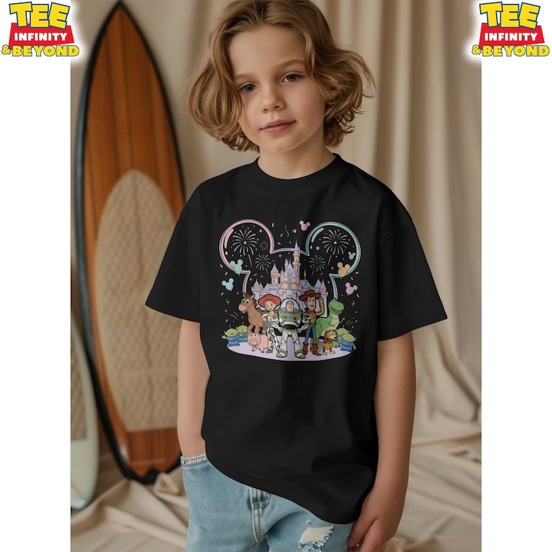 May include: Black t-shirt featuring a colorful graphic of Disney's Toy Story characters in front of a castle, with fireworks and Mickey Mouse ears. The shirt is worn by a child.