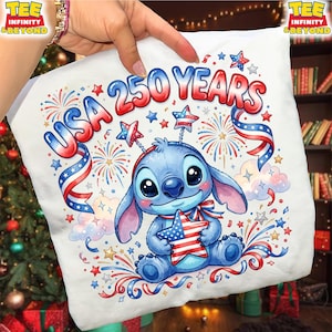 May include: White t-shirt featuring a cartoon character holding a star with the American flag design. The shirt has the text "USA 250 YEARS" in red, white, and blue, with fireworks and star accents. The design celebrates the USA.