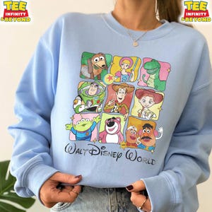 Puede incluir: Sudadera azul claro con un dise&ntilde;o colorido de personajes de Toy Story en una cuadr&iacute;cula. El dise&ntilde;o incluye im&aacute;genes de Slinky Dog, Bo Peep, Rex, Buzz Lightyear, Woody, Jessie, un extraterrestre, Lotso, Sr. Cara de Papa y Sra. Cara de Papa. Las palabras "Walt Disney World" est&aacute;n impresas debajo.