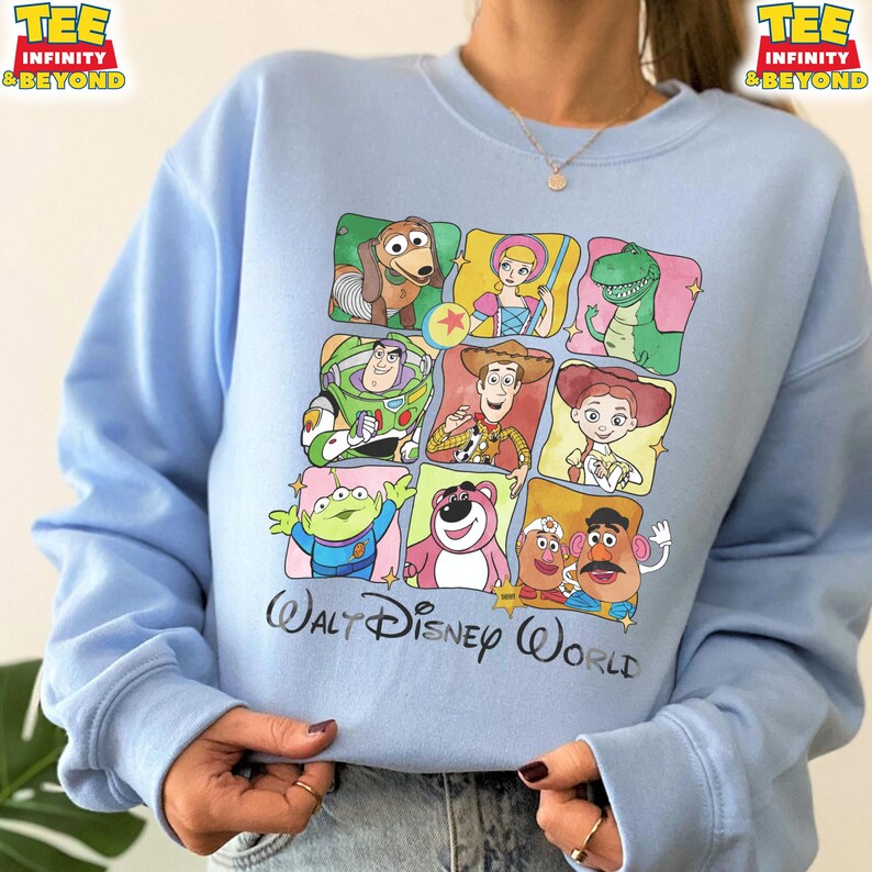 Puede incluir: Sudadera azul claro con un dise&ntilde;o colorido de personajes de Toy Story en una cuadr&iacute;cula. El dise&ntilde;o incluye im&aacute;genes de Slinky Dog, Bo Peep, Rex, Buzz Lightyear, Woody, Jessie, un extraterrestre, Lotso, Sr. Cara de Papa y Sra. Cara de Papa. Las palabras "Walt Disney World" est&aacute;n impresas debajo.