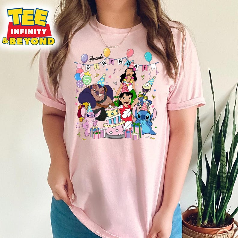 May include: A pale pink t-shirt with a vibrant graphic of Lilo & Stitch characters. The design includes a birthday cake, balloons, and the text "Amanda Birthday 5". The tee has short sleeves and a round neck.