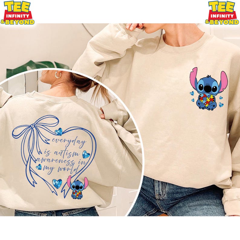 May include: Beige sweatshirt featuring a blue cartoon character holding a puzzle piece heart, with blue butterflies. The back of the sweatshirt has a blue heart-shaped design with the text "everyday is autism awareness in my world."