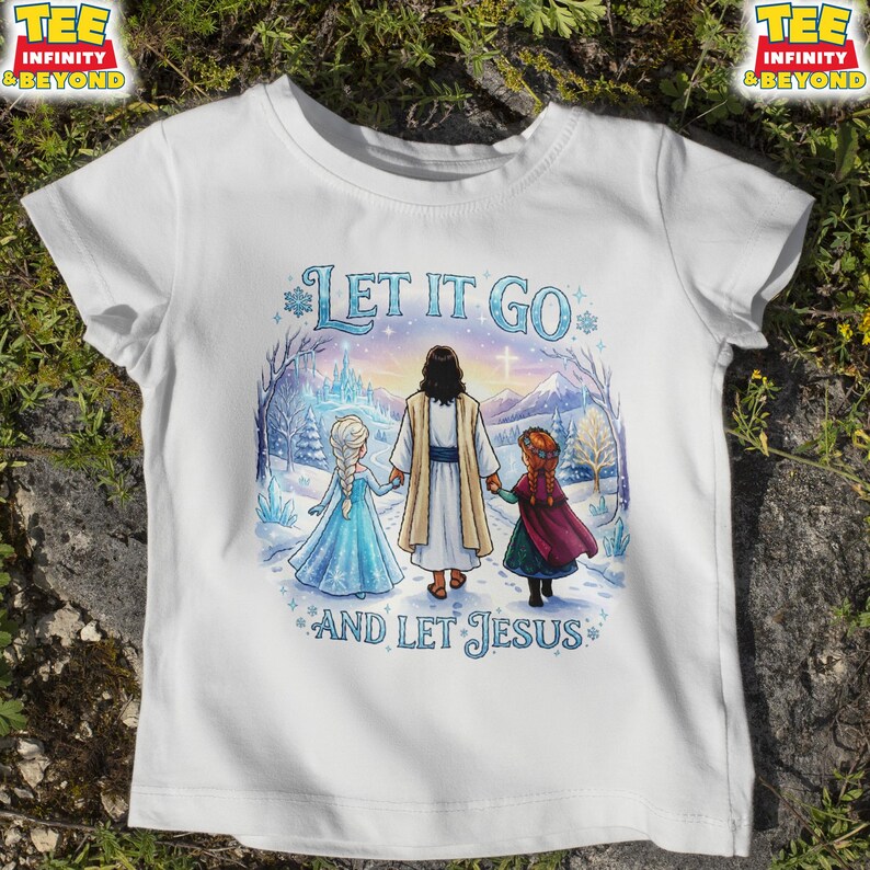 以下が含まれることがあります： 「LET IT GO」と「AND LET JESUS」の文字が入った白いTシャツ。イエスと2人の少女が雪景色の中にいるイラストが描かれています。