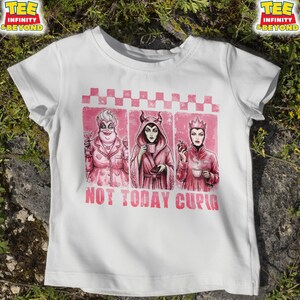 May include: White t-shirt featuring a pink graphic with three cartoon villains, each holding a drink or an apple. The text "NOT TODAY CUPID" is printed in pink below the graphic. The shirt has short sleeves and a crew neck.