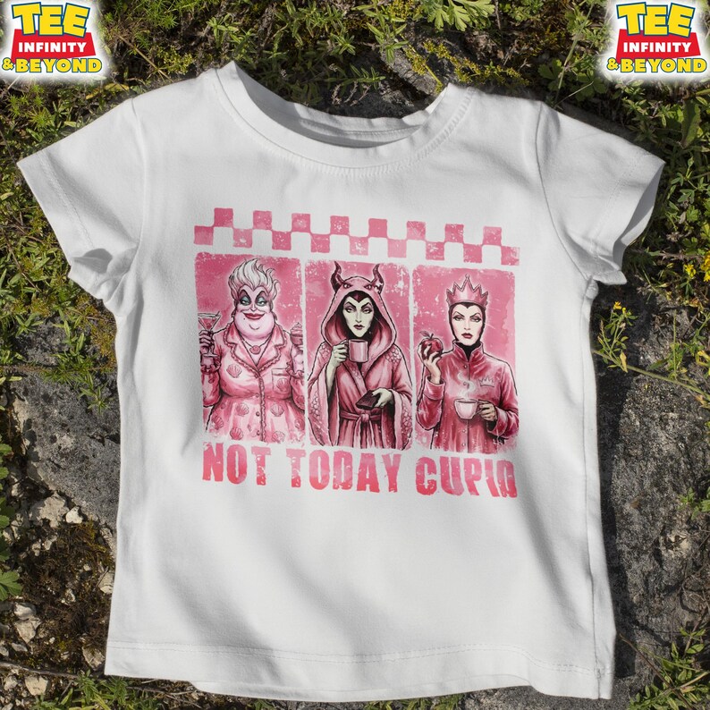 May include: White t-shirt featuring a pink graphic with three cartoon villains, each holding a drink or an apple. The text "NOT TODAY CUPID" is printed in pink below the graphic. The shirt has short sleeves and a crew neck.