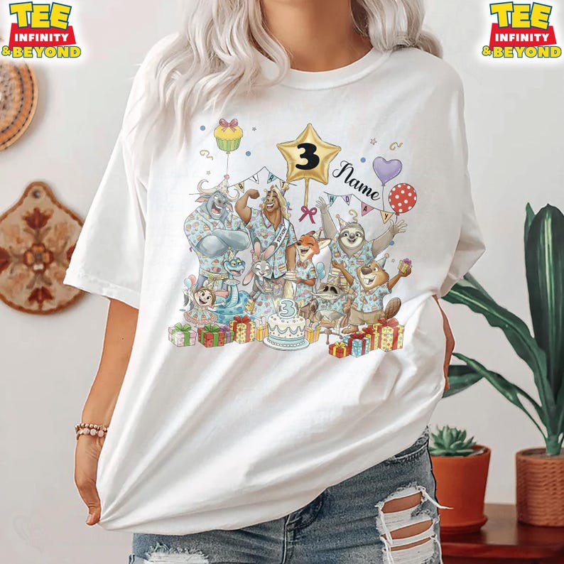 Puede incluir: Camiseta blanca con un gr&aacute;fico colorido de animales de dibujos animados celebrando un cumplea&ntilde;os. El dise&ntilde;o incluye una estrella dorada con el n&uacute;mero 3, una tarta, globos y la palabra "Name". La camiseta tiene las palabras "TEE INFINITY & BEYOND" impresas en la parte superior.
