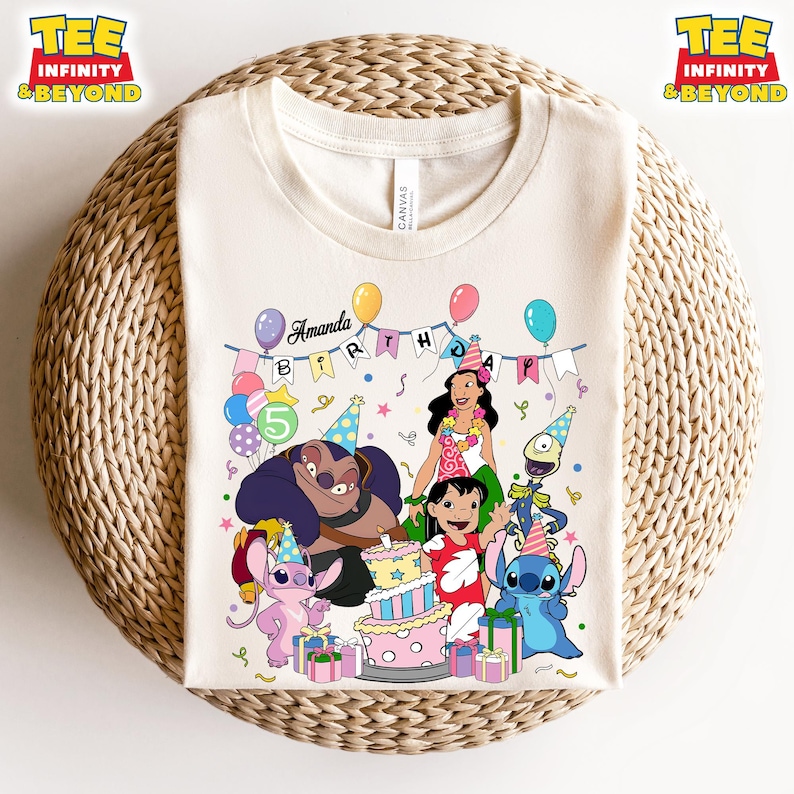 May include: A cream-coloured t-shirt with a vibrant graphic of animated characters, a birthday cake, and balloons. The text "Amanda Birthday" is above the characters. The shirt has the text "TEE INFINITY & BEYOND" on the top left and right.