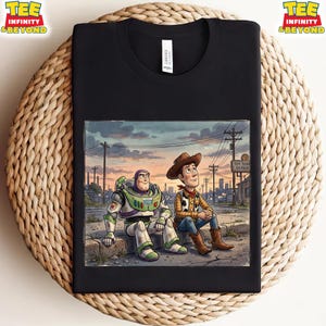 May include: Black t-shirt with a colourful illustration of Buzz Lightyear and Woody from Toy Story. The image shows them sitting together with a sunset backdrop and the words "Toy Town Repair". The shirt has the words "TEE INFINITY & BEYOND" printed on it.