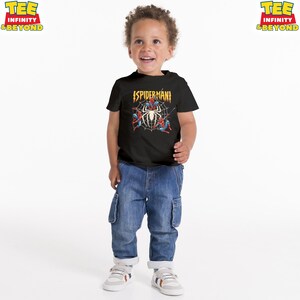 May include: A black Spider-Man t-shirt with a graphic of Spider-Man in a web. The shirt has the text "SPIDERMAN" in yellow. The child is wearing blue jeans and white sneakers.