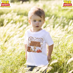 May include: A white short-sleeved t-shirt featuring a western-themed graphic with a lasso, cowboy boots, a hat, and the text "I KNEW IT I KNEW YOU 5" along with "YOU'VE GOT A FRIEND" and "Infinity and Beyond" in brown, red, and blue colors.