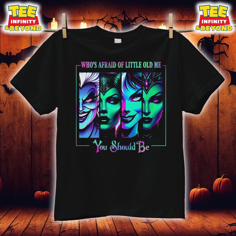 May include: Black t-shirt featuring a graphic of four villainous characters with vibrant green and purple hues. The text "WHO'S AFRAID OF LITTLE OLD ME" and "You Should Be" are displayed in white and purple.