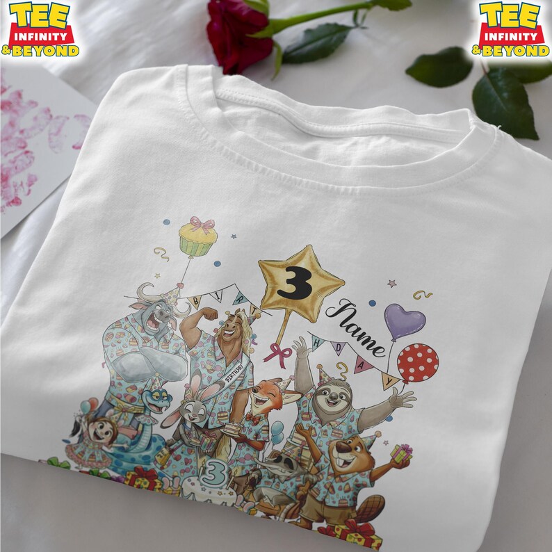 Puede incluir: Camiseta blanca con un gr&aacute;fico colorido de animales de dibujos animados celebrando un cumplea&ntilde;os. El dise&ntilde;o incluye globos, un globo en forma de estrella con el n&uacute;mero 3 y la palabra "Name". La camiseta tiene el texto "TEE INFINITY & BEYOND".