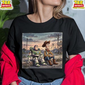 May include: Black t-shirt with a cartoon image of Buzz Lightyear and Woody from Toy Story. They are sitting together with a cityscape backdrop, and the words "Toy Town Repair" are visible.