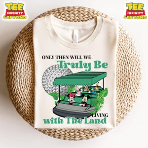 Könnte beinhalten: Ein beiges T-Shirt mit einer grün-weißen Illustration einer Fahrt im Epcot-Themenpark von Disney World. Der Text "Only then will we Truly Be Living with The Land" ist auf das Shirt gedruckt.