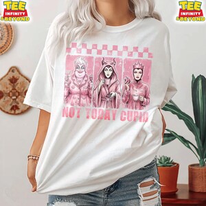 May include: White t-shirt featuring a pink graphic with three cartoon villains and the text "NOT TODAY CUPID." The graphic has a pink checkered border. The shirt has short sleeves and a crew neck.
