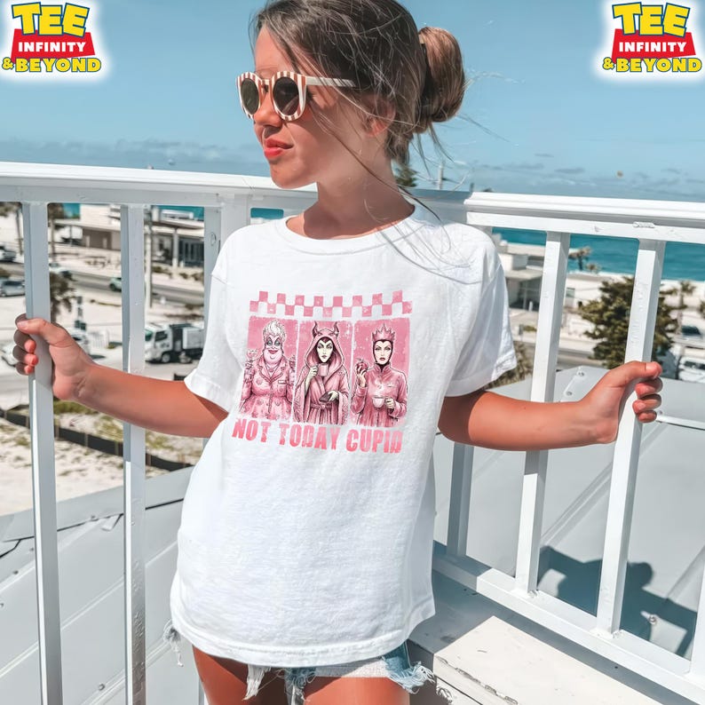 May include: White t-shirt featuring a pink graphic of three cartoon characters with the text "NOT TODAY CUPID". The shirt has a crew neck and short sleeves. The tee has the logo "TEE INFINITY & BEYOND" in the top corners.