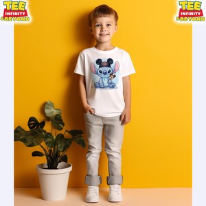 K&ouml;nnte beinhalten: Ein wei&szlig;es T-Shirt mit einem Cartoon-Stitch-Charakter, der einen Mickey-Mouse-Hut tr&auml;gt und ein Mickey-Mouse-Pl&uuml;schtier h&auml;lt. Das T-Shirt wird von einem kleinen Kind getragen. Die Worte "TEE INFINITY & BEYOND" sind oben links und rechts aufgedruckt.