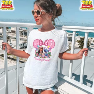 May include: White t-shirt featuring a pink Minnie Mouse-shaped design with a bow, the number 9, and the words "Birthday Princess." The design includes cartoon characters and balloons. The shirt is worn by a person.