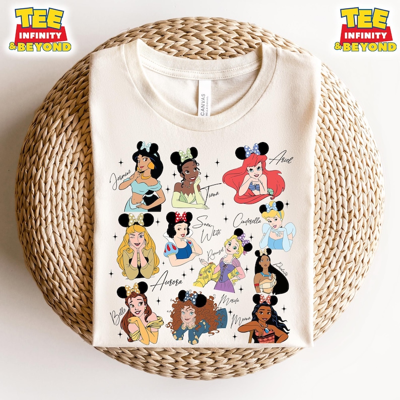 May include: A white t-shirt with a design of 12 Disney princesses with mouse ears. The princesses include Belle, Aurora, Snow White, Cinderella, Ariel, Tiana, Jasmine, Pocahontas, Mulan, Rapunzel, Merida, and Moana.