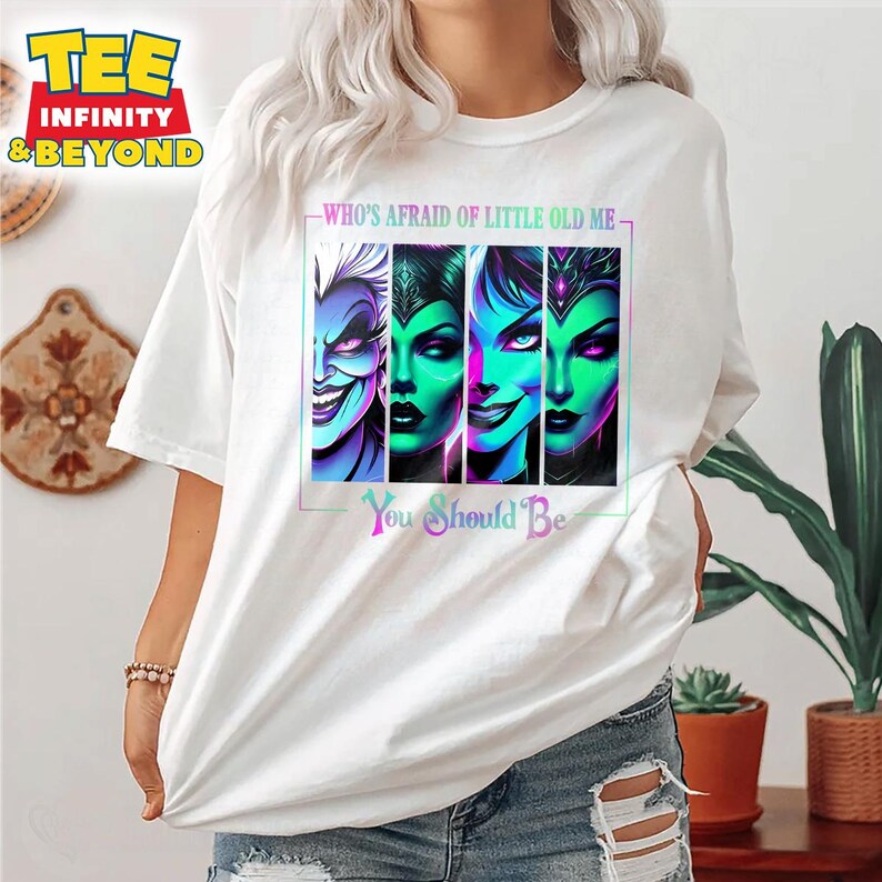 May include: White t-shirt featuring a colorful graphic of four villainous characters with the text "WHO'S AFRAID OF LITTLE OLD ME" and "You Should Be". The graphic has a neon color scheme.