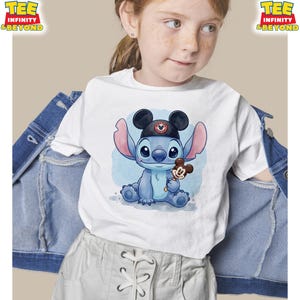 K&ouml;nnte beinhalten: Wei&szlig;es T-Shirt mit einer Cartoon-Illustration von Stitch, der einen Mickey-Mouse-Hut tr&auml;gt und ein Mickey-Mouse-Eis h&auml;lt. Das Shirt hat den Text "TEE INFINITY & BEYOND" oben links und rechts.