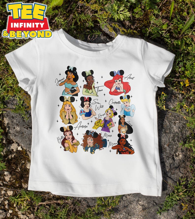 May include: White t-shirt with a graphic of Disney princesses wearing mouse ears. The princesses include Jasmine, Tiana, Ariel, Snow White, Cinderella, Aurora, Belle, Mulan, and  Mowgli. Each princess has her name written next to her.