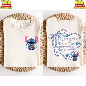 May include: Two cream-colored t-shirts. One features a blue cartoon character holding a puzzle piece, with blue puzzle pieces. The other shirt has a blue heart-shaped design with the text "everyday is autism awareness in my world."