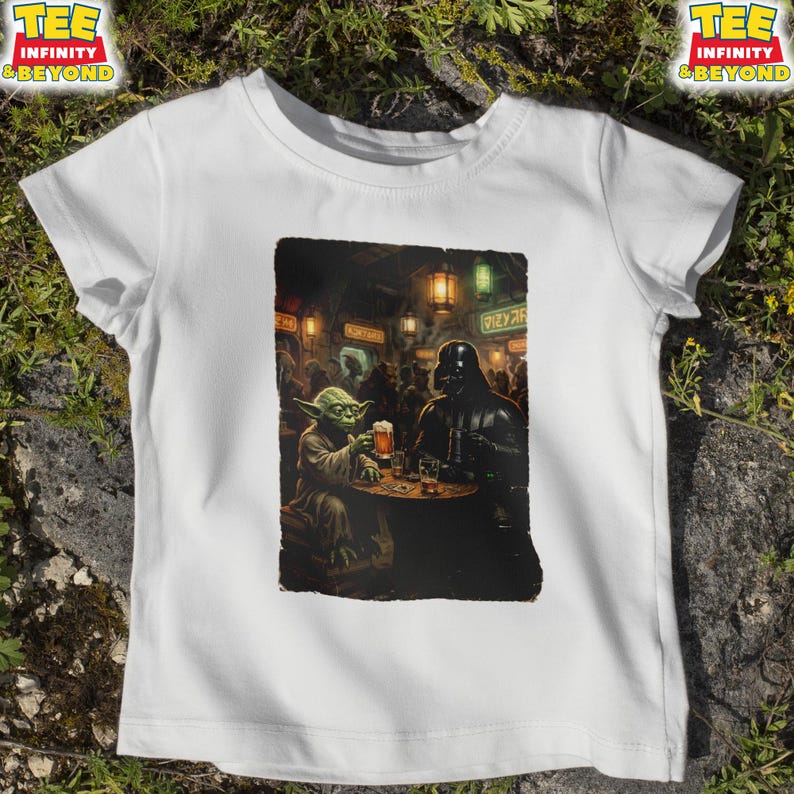 K&ouml;nnte beinhalten: Wei&szlig;es T-Shirt mit einer humorvollen Illustration von Yoda und Darth Vader in einer Bar, die jeweils ein Bier halten. Das Bild ist mit einem schwarzen Rand versehen. Das Shirt hat den Text "TEE INFINITY & BEYOND" oben links und rechts.