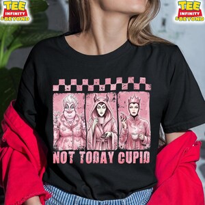 May include: Black t-shirt featuring a pink graphic with three cartoon villains: Ursula, Maleficent, and the Evil Queen. The text "NOT TODAY CUPID" is below the images. The shirt has a crew neck and short sleeves.