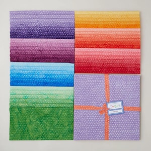 May include: A collection of colorful fabric squares in shades of purple, blue, green, orange, and red. The fabrics have a dotted pattern. A square bundle is tied with orange ribbon and a tag that reads "Jan Burlk".