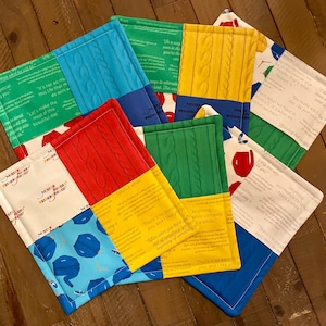 May include: Set of six colorful quilted fabric coasters with different patterns and inspirational quotes. The quotes include "Let's make the most of this beautiful day", "Anything worthwhile certainly takes a while", and "There's no person like you, and I like you just as you are".