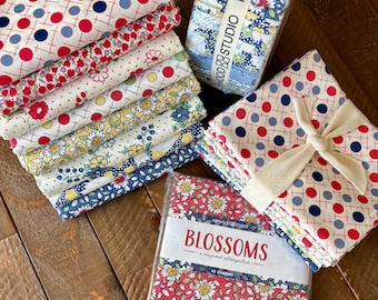 May include: A collection of patterned fabric bundles in red, white, and blue, featuring floral and polka dot designs. One bundle is tied with a cream ribbon. The image also includes a package labeled "BLOSSOMS" and a bundle with the text "MAYWOOD STUDIO".