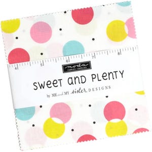 May include: A stack of fabric squares with a white background and colorful polka dots in pink, yellow, and blue. The fabric is wrapped with a band that reads "SWEET AND PLENTY" and "ME and MY sister DESIGNS".