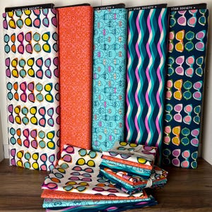May include: A collection of colorful fabric rolls and folded fabric pieces. The rolls feature various patterns, including sunglasses, geometric shapes, and wavy lines. The color palette includes white, orange, blue, and navy. The folded fabric displays a sunglasses pattern.