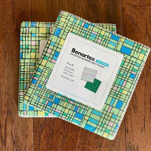 May include: Two stacks of 5" x 5" fabric squares with a green, blue, and pink grid pattern. The label reads "Benartex CONTEMPO DELIGHT BY MODERN QUILT STUDIO" and states the fabric is 100% cotton. The text "CUT AND ASSEMBLED IN THE USA" is also visible.