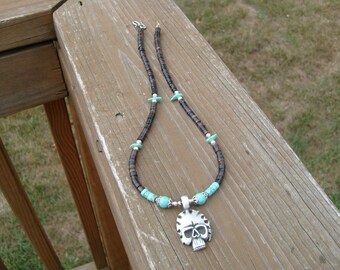 May include: A brown and black beaded necklace with turquoise accents and a silver skull pendant.