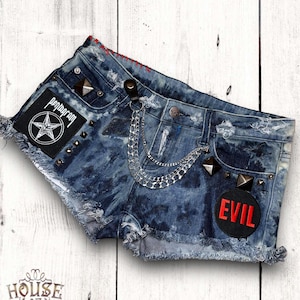May include: Distressed denim shorts with a pentagram patch, metal studs, and a chain attached to the belt loops. The shorts also have a black patch with the word "EVIL" in red lettering.