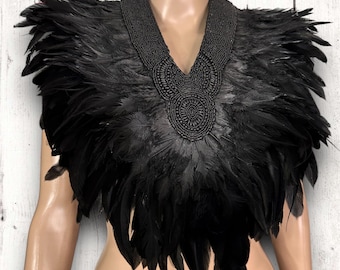 May include: A black feather collar with a beaded design. The collar is made of black feathers and has a beaded design around the neck. The collar is worn by a mannequin.