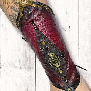 Brazalete de cuero de vaca con tachuelas de latón negro, color ciruela vino, hecho a mano, de estilo místico oscuro. Accesorio para disfraces de fantasía y ferias renacentistas.