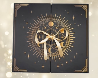 May include: A black box with a celestial design in gold, featuring a sun, moons, and stars. The box is tied with a gold ribbon. The corners have gold geometric accents. The box is closed.