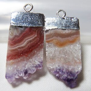 May include: Two silver-capped pendants with amethyst crystals. The crystals are a mix of white, pink, and purple with a layered, banded pattern.