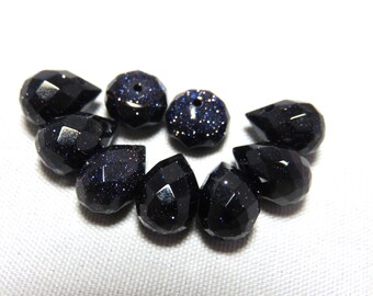 May include: A collection of eight black gemstone beads with a sparkly, speckled finish. The beads are faceted and have a teardrop shape. Two of the beads are round.
