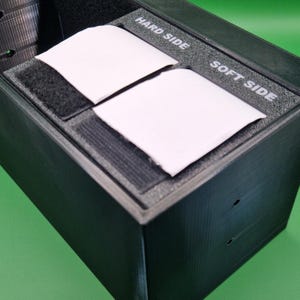 May include: A black box with two white rectangular inserts. The inserts have black velcro on the bottom and the text "HARD SIDE" and "SOFT SIDE" on the top.
