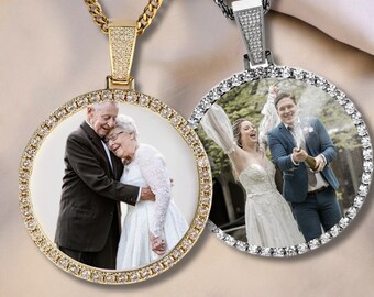 May include: Two gold and silver pendants with a round photo frame. The pendants feature a diamond-like border and are on a chain. The photo on the left shows an older couple embracing, while the photo on the right shows a bride and groom.