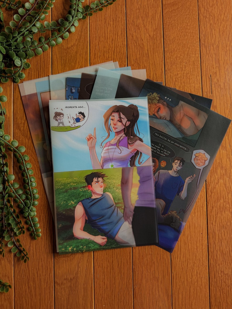 May include: A stack of illustrated art prints featuring colorful artwork. The prints showcase various scenes with figures in different settings. One print has the text "Moments Ago..." and another has the text "This better be an emergency..."