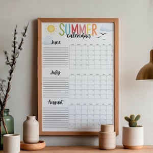 Op de afbeelding: Een zomerkalender in een houten frame, met juni, juli en augustus. De kalender heeft een kleurrijke "Summer Calendar"-kop met een zon, wolken en vogels. Elke maand heeft een gelijnde sectie voor notities en een raster voor data.