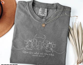 May include: A gray Comfort Colors t-shirt with a white line drawing of a cow and bull. The text "Follow the word not the herd. Isaiah 8:11-13" is printed below the drawing. A gold necklace is on the shirt.