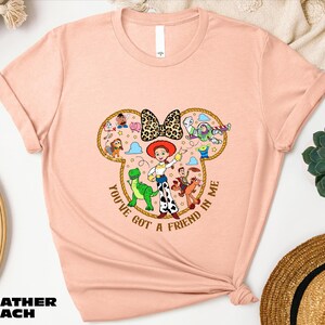 A pink t-shirt with a cartoon character design and text, along with some other items such as a straw hat and a potted plant.